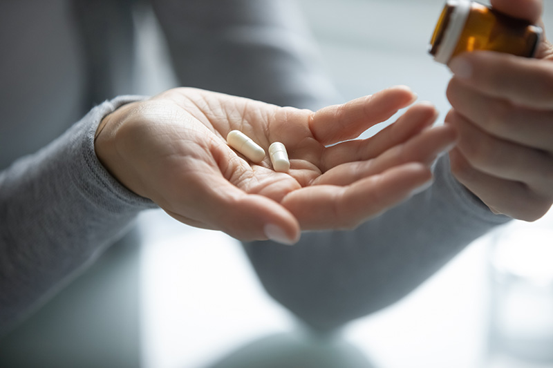 A person holding pills for sedation dentistry for procedures like periodontal surgery or wisdom teeth removal.